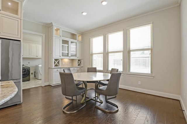 dining space with washing machine and dryer, a wealth of natural light, dark hardwood / wood-style flooring, and crown molding