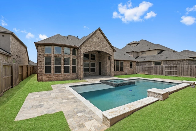 rear view of property with a lawn, a patio, and a pool with hot tub