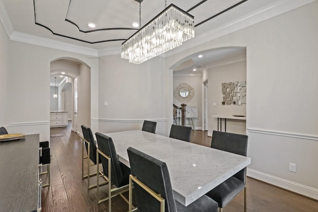 dining room with dark wood-type flooring, ornamental molding, and a notable chandelier