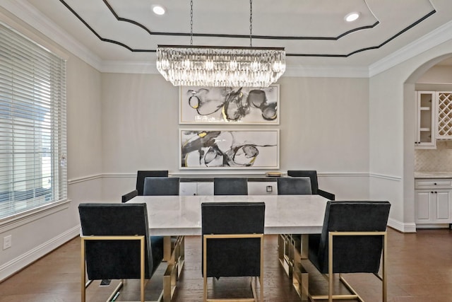 dining area with dark hardwood / wood-style floors, ornamental molding, and an inviting chandelier