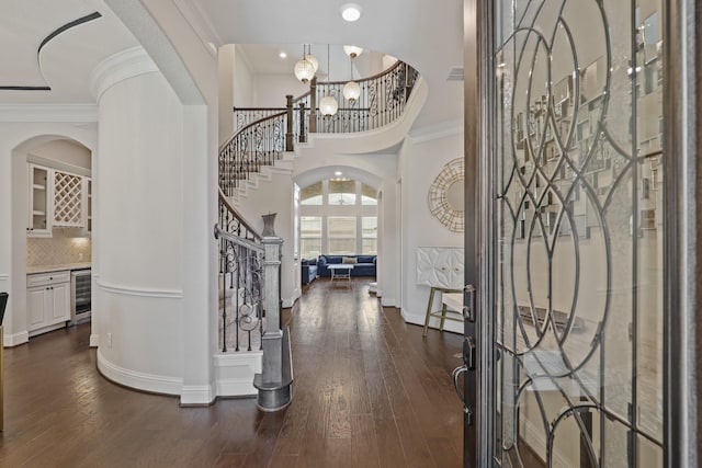 entrance foyer with crown molding, wine cooler, and dark wood-type flooring