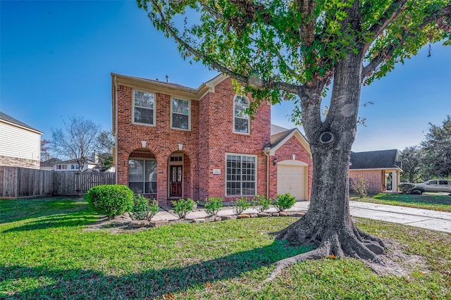 traditional-style home featuring a front yard, fence, driveway, a garage, and brick siding