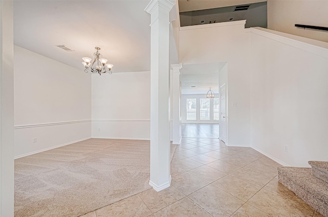 tiled spare room with an inviting chandelier, decorative columns, visible vents, and carpet floors