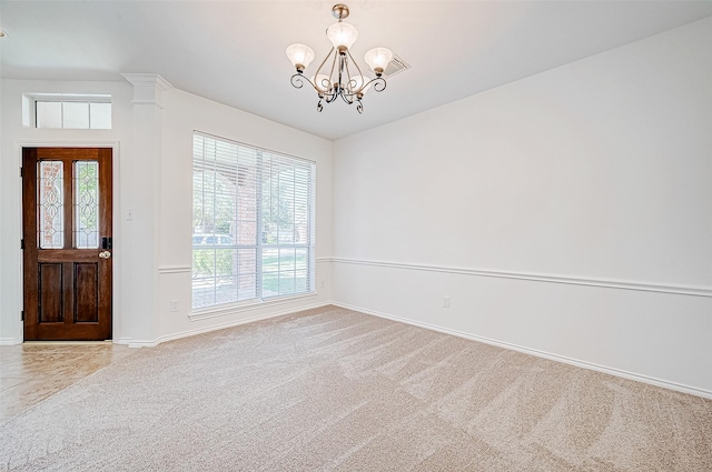 carpeted empty room featuring baseboards and a chandelier