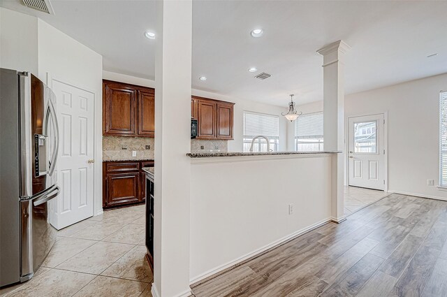 kitchen featuring a wealth of natural light, visible vents, backsplash, and stainless steel refrigerator with ice dispenser