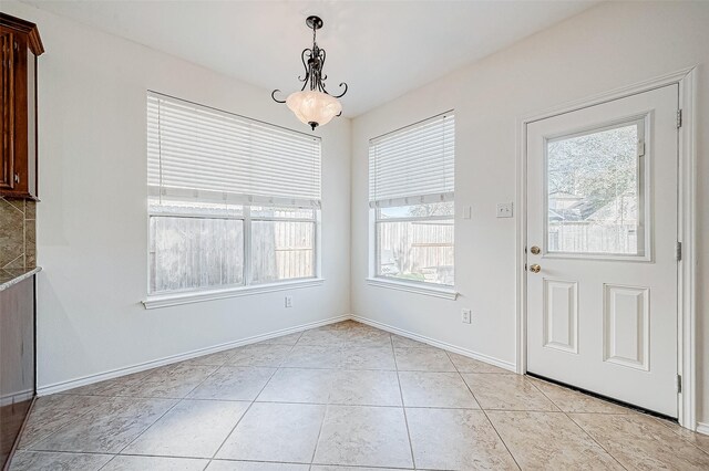 unfurnished dining area with light tile patterned floors and baseboards