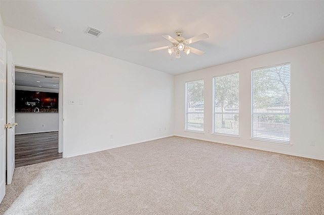 unfurnished room featuring baseboards, visible vents, carpet floors, and ceiling fan