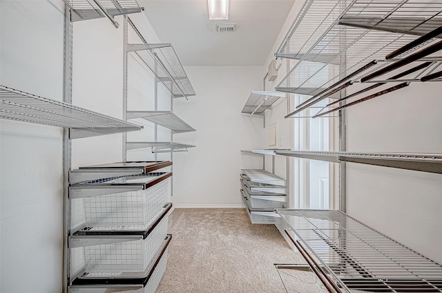 walk in closet featuring visible vents and light carpet