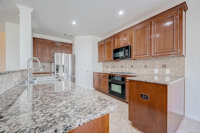 kitchen with tasteful backsplash, light stone counters, sink, black appliances, and light tile patterned flooring