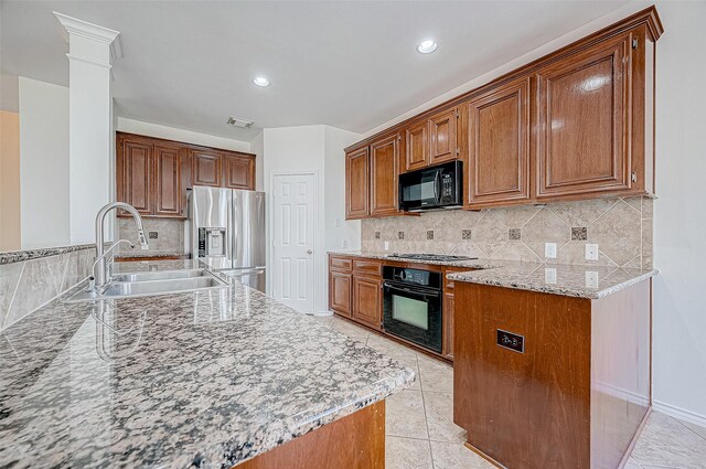 kitchen featuring light tile patterned floors, a sink, black appliances, brown cabinets, and backsplash