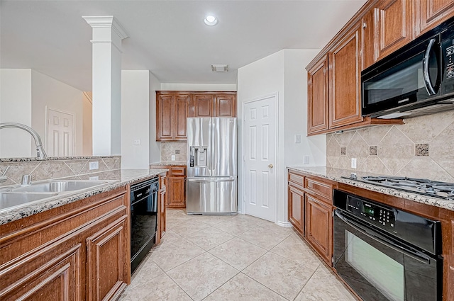 kitchen featuring tasteful backsplash, light stone countertops, sink, and black appliances