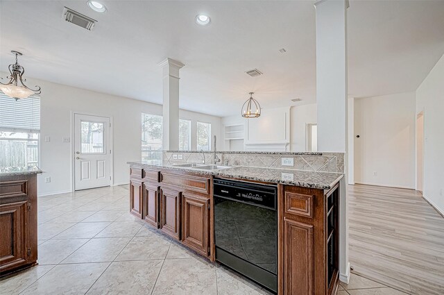 kitchen with black dishwasher, ornate columns, hanging light fixtures, and sink