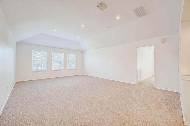 unfurnished room with lofted ceiling, visible vents, and light carpet