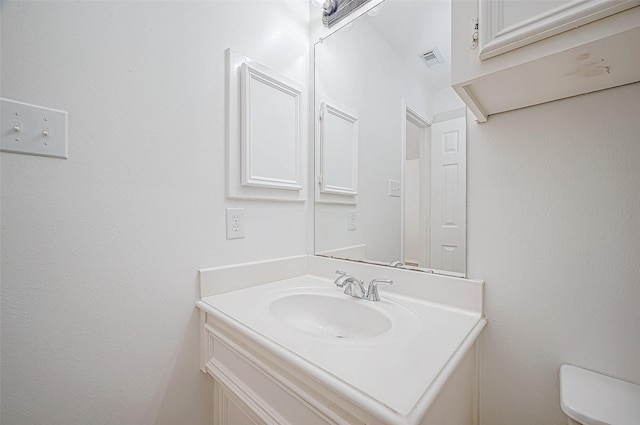 bathroom with vanity, toilet, and visible vents