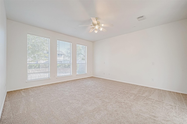 spare room featuring a ceiling fan, visible vents, carpet floors, and baseboards