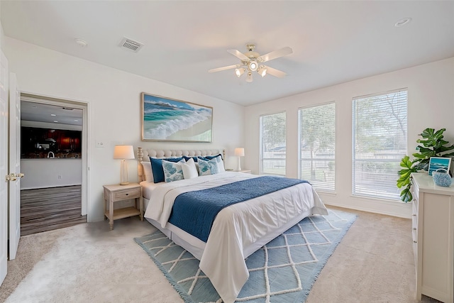 bedroom with multiple windows, light colored carpet, and ceiling fan