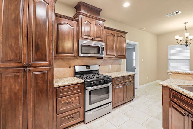 kitchen with hanging light fixtures, an inviting chandelier, light stone counters, decorative backsplash, and appliances with stainless steel finishes