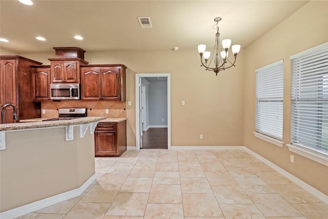 kitchen with light stone countertops, stove, decorative backsplash, decorative light fixtures, and a notable chandelier