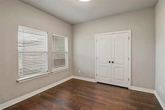 unfurnished bedroom featuring a closet and dark wood-type flooring