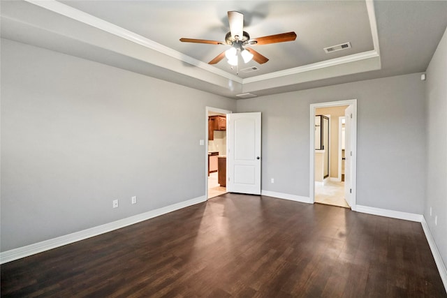 unfurnished bedroom with ceiling fan, dark hardwood / wood-style floors, crown molding, and a tray ceiling