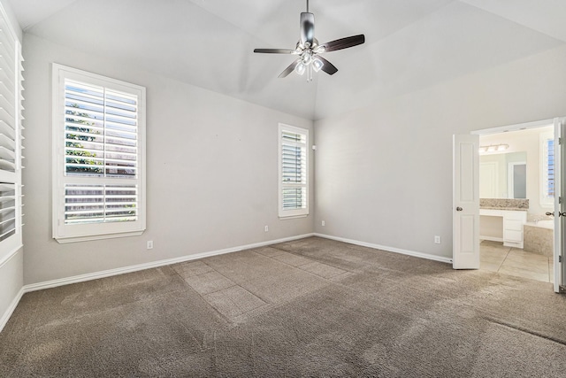 empty room featuring light colored carpet, vaulted ceiling, a wealth of natural light, and ceiling fan