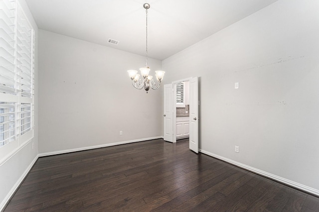 spare room with dark hardwood / wood-style floors and a notable chandelier