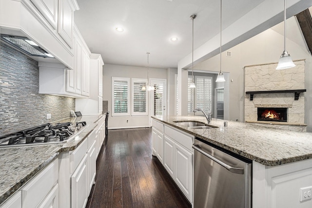 kitchen with hanging light fixtures, a center island with sink, white cabinets, and stainless steel appliances