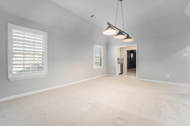 carpeted empty room featuring vaulted ceiling