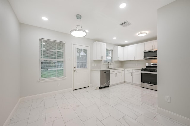 kitchen with white cabinets, decorative light fixtures, sink, and appliances with stainless steel finishes