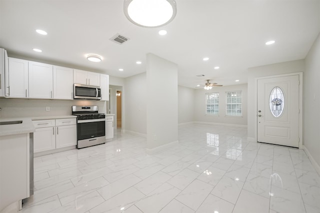 kitchen with white cabinets, ceiling fan, sink, and stainless steel appliances