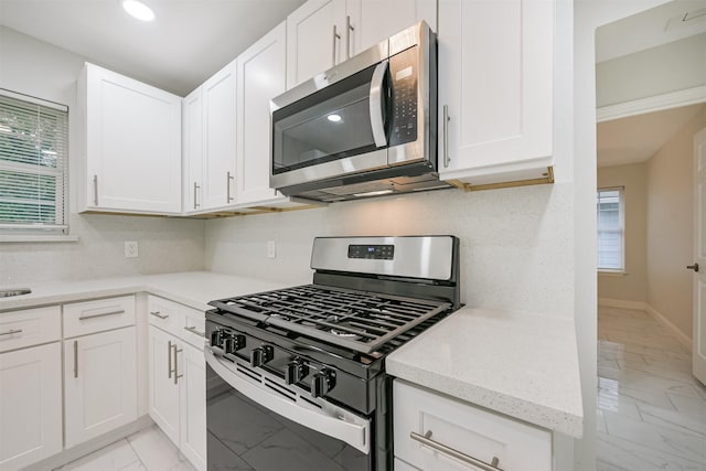 kitchen with white cabinets, light stone counters, and appliances with stainless steel finishes