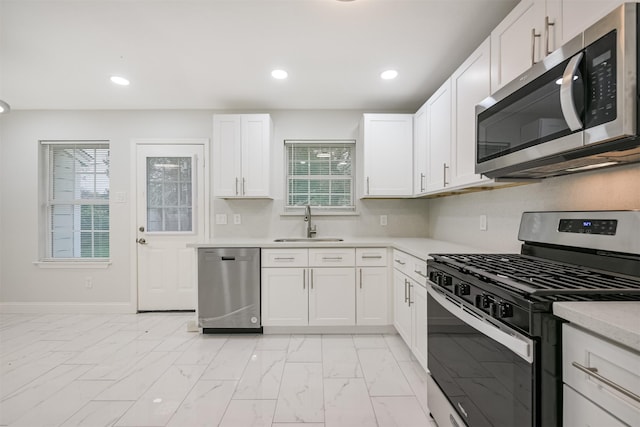 kitchen featuring stainless steel appliances, white cabinetry, and sink