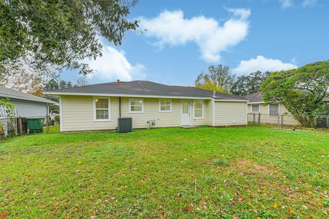 rear view of house featuring central air condition unit and a lawn