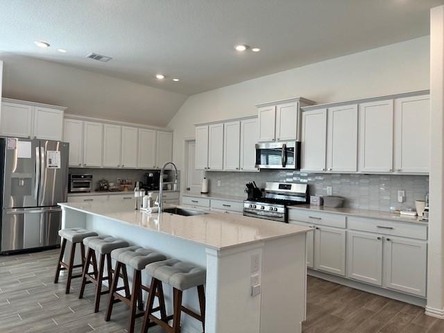 kitchen with white cabinets, sink, stainless steel appliances, and a kitchen island with sink