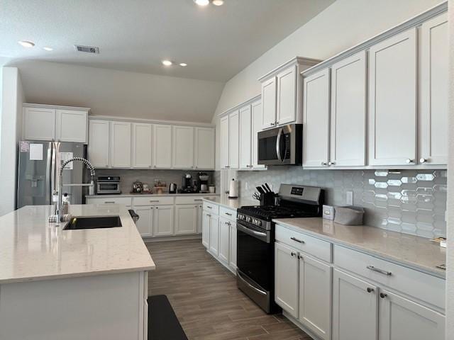 kitchen featuring backsplash, light stone counters, stainless steel appliances, sink, and white cabinets