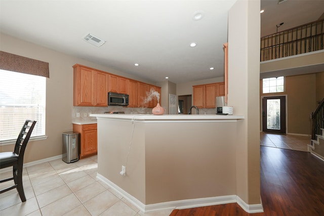 kitchen with sink, light tile patterned floors, tasteful backsplash, kitchen peninsula, and stainless steel appliances