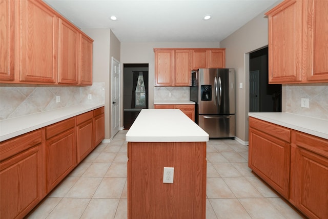 kitchen featuring backsplash, stainless steel fridge with ice dispenser, a kitchen island, and light tile patterned floors