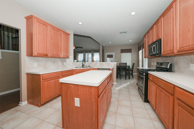 kitchen with tasteful backsplash, stainless steel gas range, sink, a center island, and light tile patterned flooring