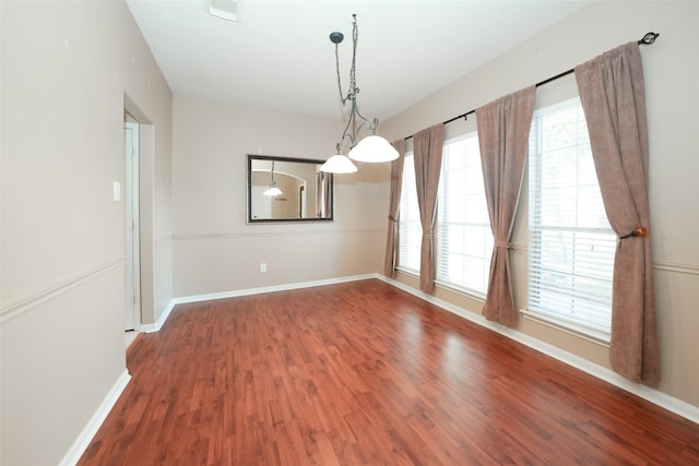 unfurnished dining area featuring plenty of natural light, a notable chandelier, and hardwood / wood-style flooring