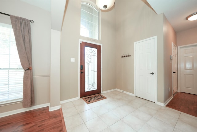 entrance foyer featuring light tile patterned floors, a towering ceiling, and a wealth of natural light