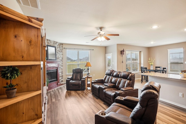 living room with a fireplace, light hardwood / wood-style floors, and ceiling fan