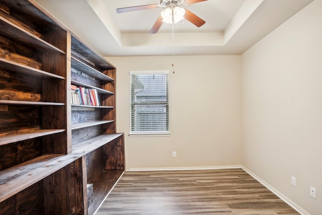 interior space with hardwood / wood-style flooring, a raised ceiling, and ceiling fan