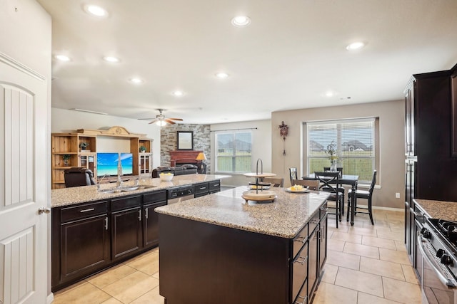 kitchen featuring stainless steel range, a center island, light stone counters, a fireplace, and light tile patterned floors