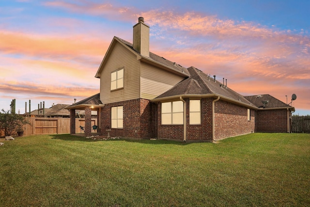 back house at dusk with a lawn