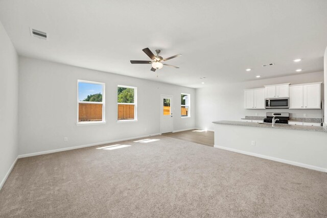 unfurnished living room featuring ceiling fan and light carpet