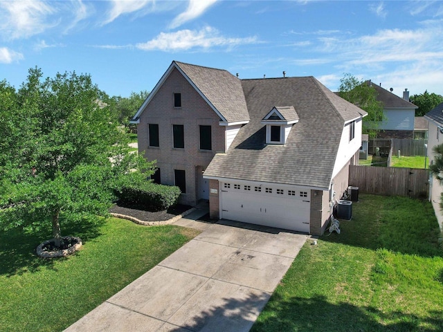 front of property with central air condition unit, a front yard, and a garage