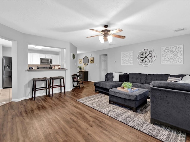 living room featuring ceiling fan, wood-type flooring, and a textured ceiling