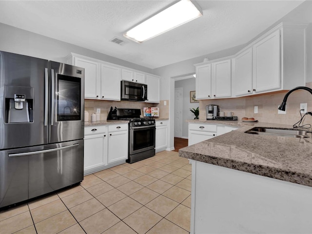 kitchen with light stone countertops, sink, stainless steel appliances, white cabinets, and light tile patterned flooring