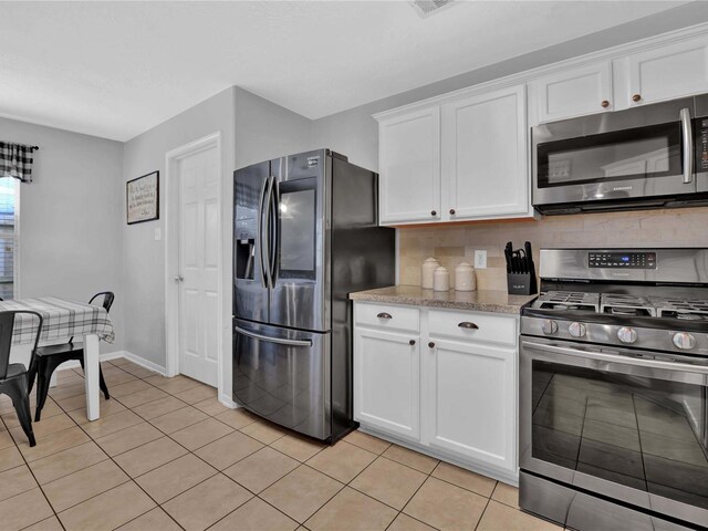 kitchen featuring appliances with stainless steel finishes, light tile patterned floors, and white cabinetry