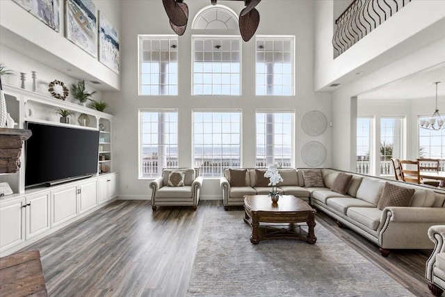 living room with ceiling fan with notable chandelier, dark hardwood / wood-style floors, a high ceiling, and ornamental molding